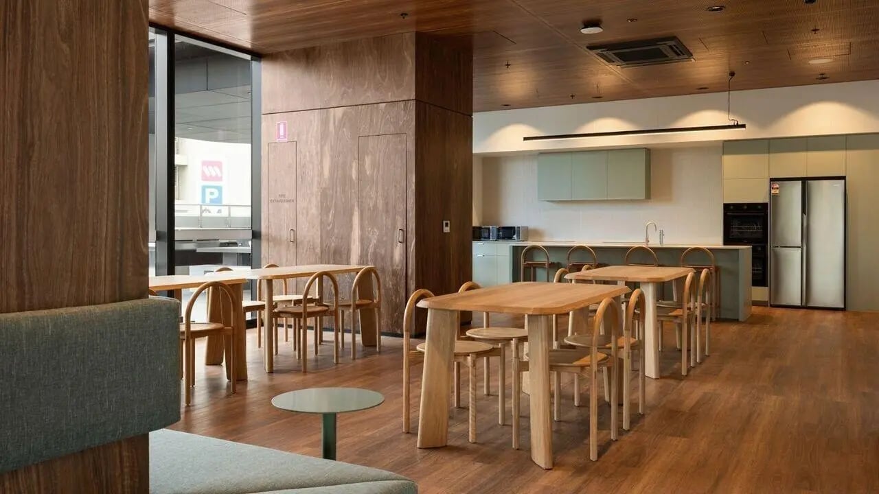 Wooden tables chairs kitchen appliances and sofa living room at UniLodge Perth Central in Perth Student Accommodation