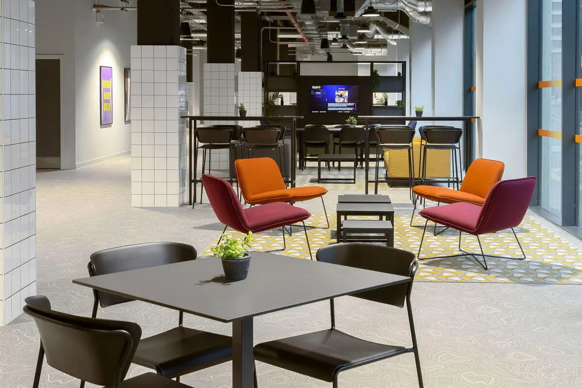 Seating area with tables chairs and plant common space at True Leicester in Leicester Student Accommodation
