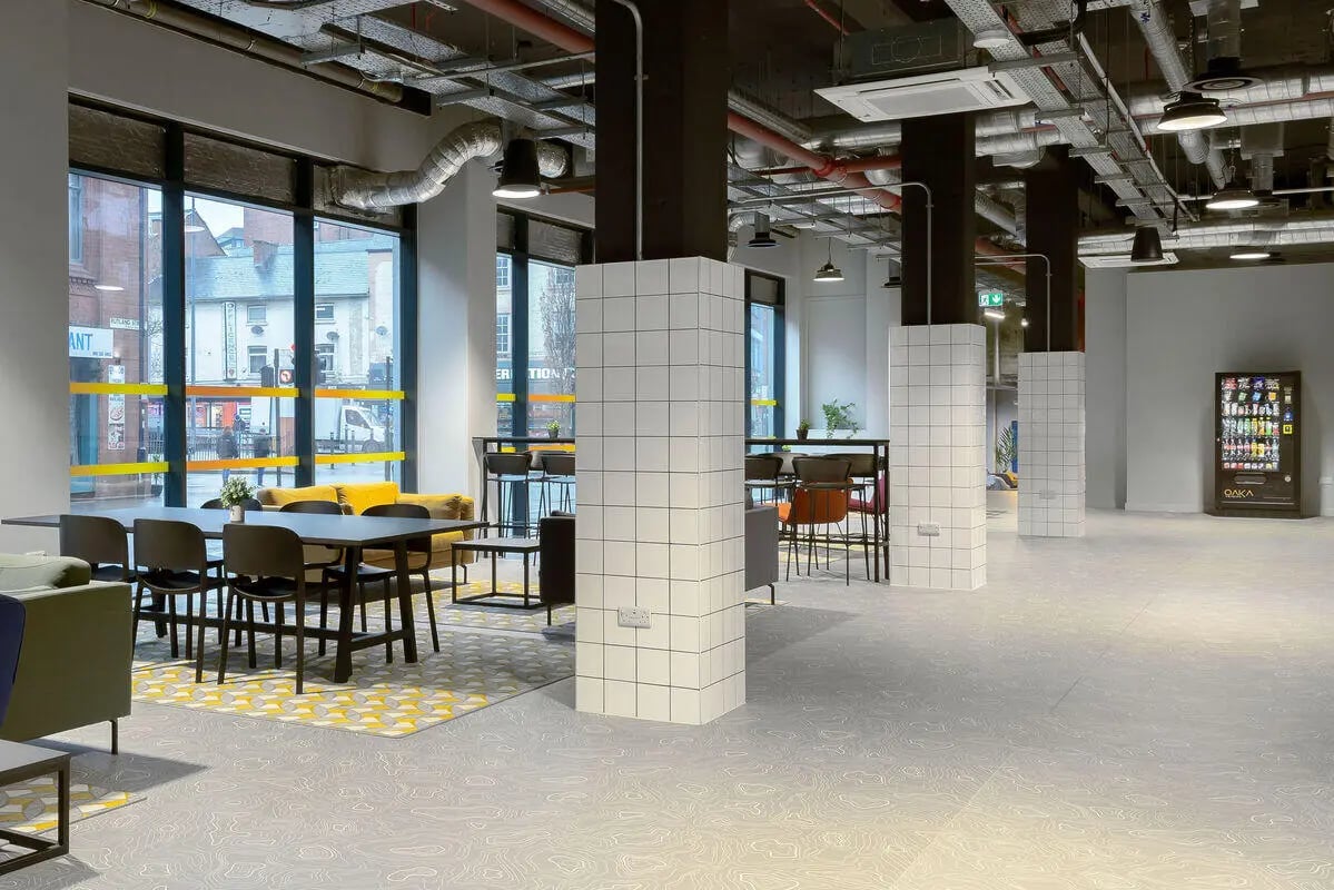 Dining table chairs yellow sofa vending machine common area at True Leicester in Leicester Student Accommodation