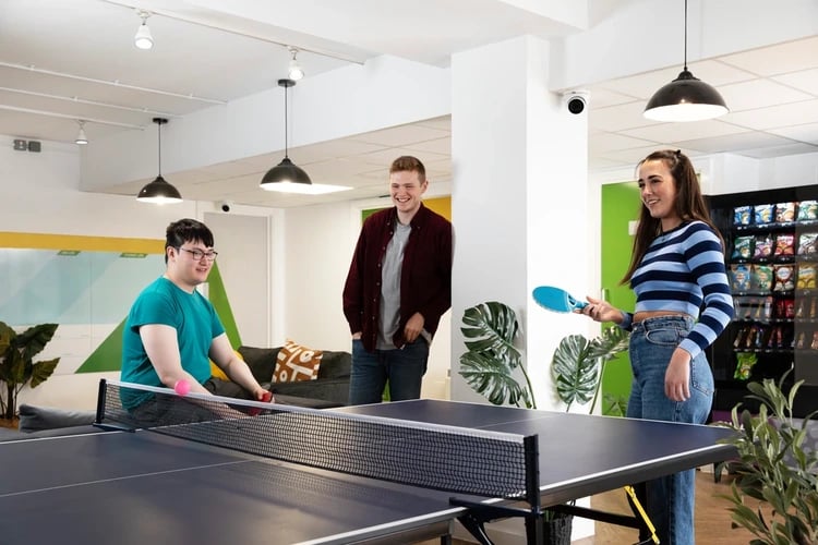 Three students play ping pong in common area. at Blackfriars in Glasgow Student Accommodation