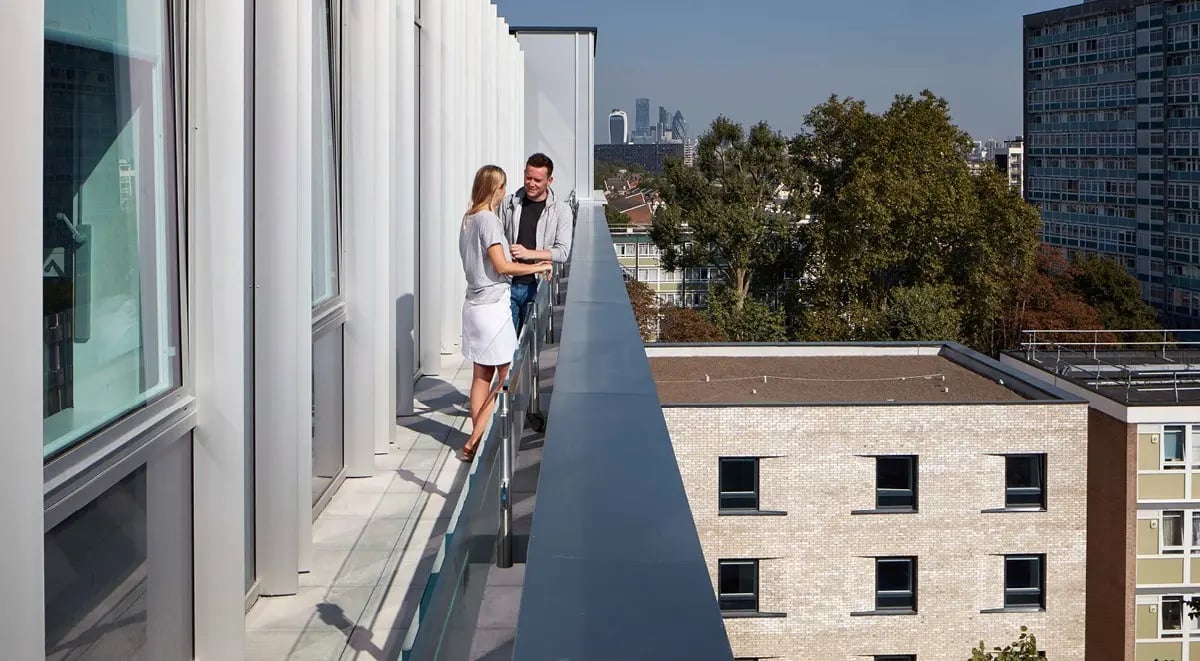 Two people on balcony overlooking city exterior at Townhall Camberwell in London Student Accommodation