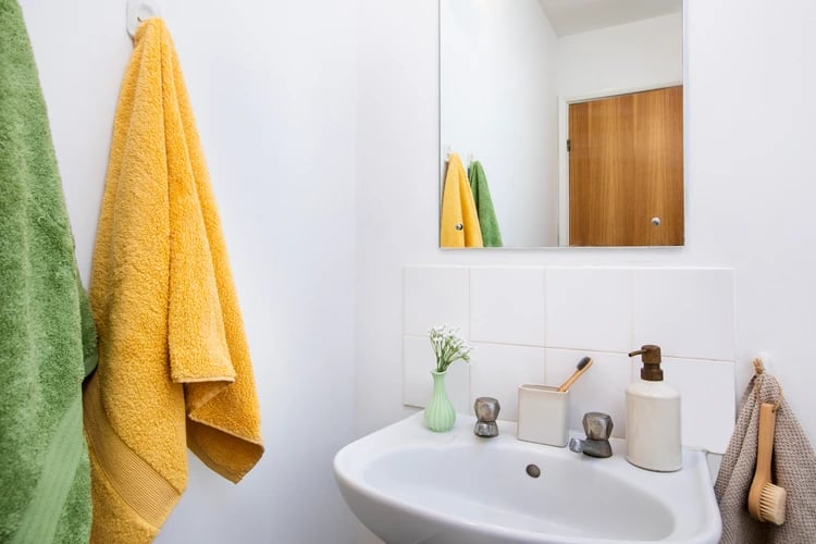 Sink with towels toothbrush soap dispenser bathroom at Ewen Henderson Court in London Student Accommodation