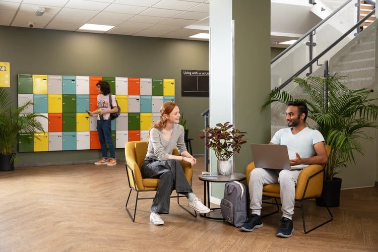 People relaxing near colorful lockers and staircase communal area at Ewen Henderson Court in London Student Accommodation
