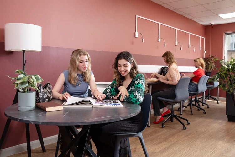 Students studying at tables with plants study area at Ewen Henderson Court in London Student Accommodation