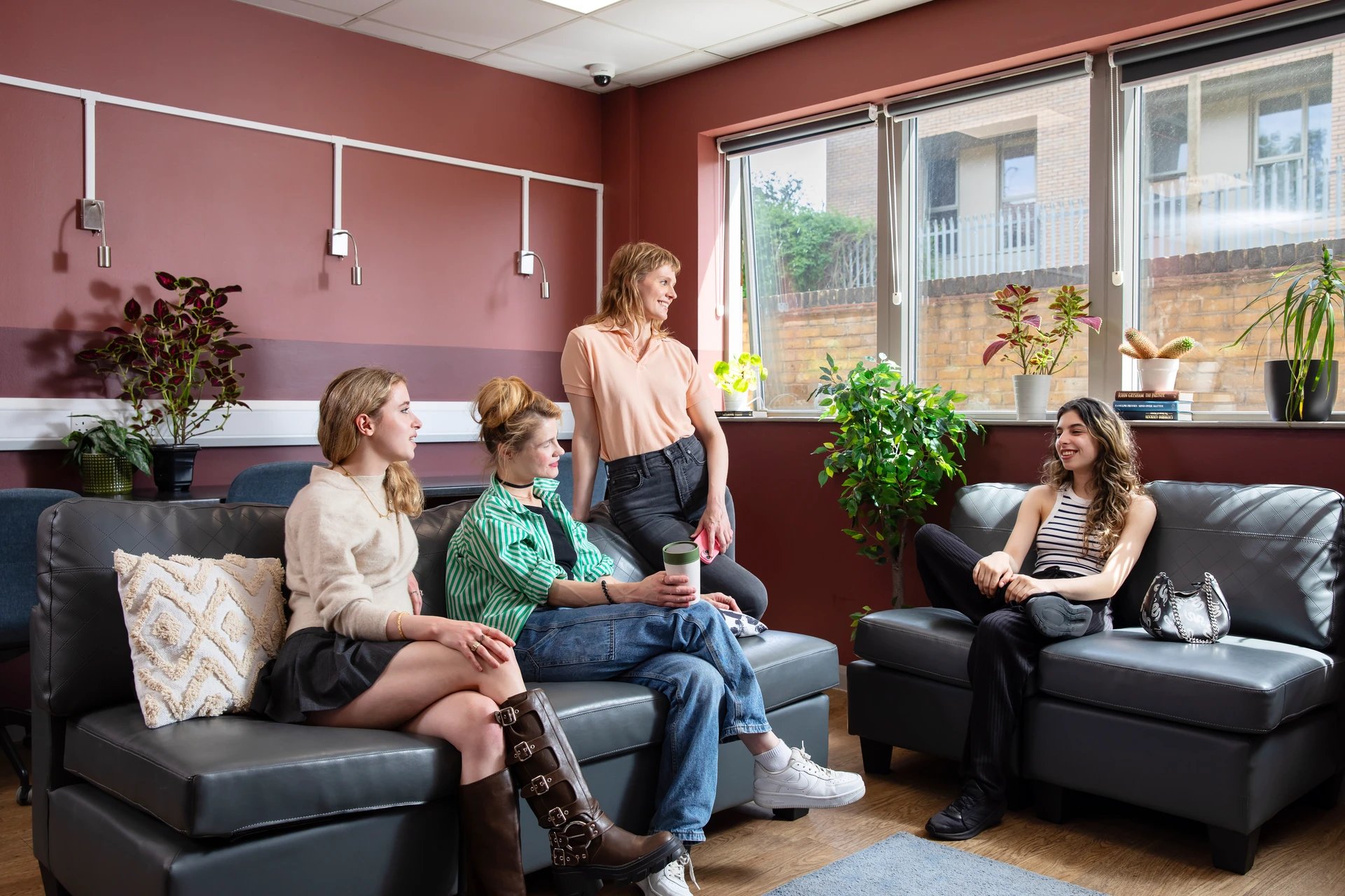 Four students relax on sofas living room at Ewen Henderson Court in London Student Accommodation