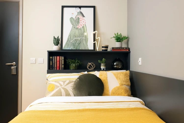 Bed with yellow blanket art shelf bedroom at Arch View House in London Student Accommodation