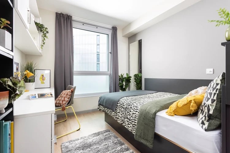 Bed desk pillows rug and shelves bedroom at Arch View House in London Student Accommodation