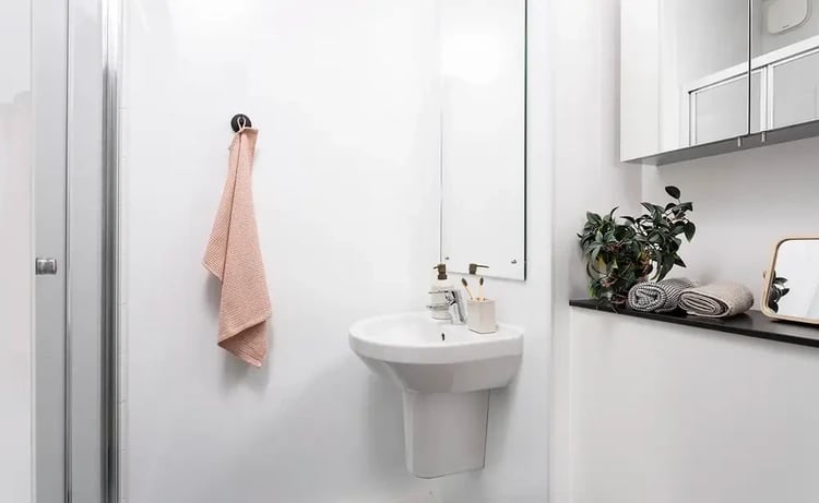 White pedestal sink pink towel plant towels bathroom at Arch View House in London Student Accommodation