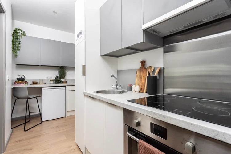 Countertop with sink stove cabinets and chair kitchen at Arch View House in London Student Accommodation