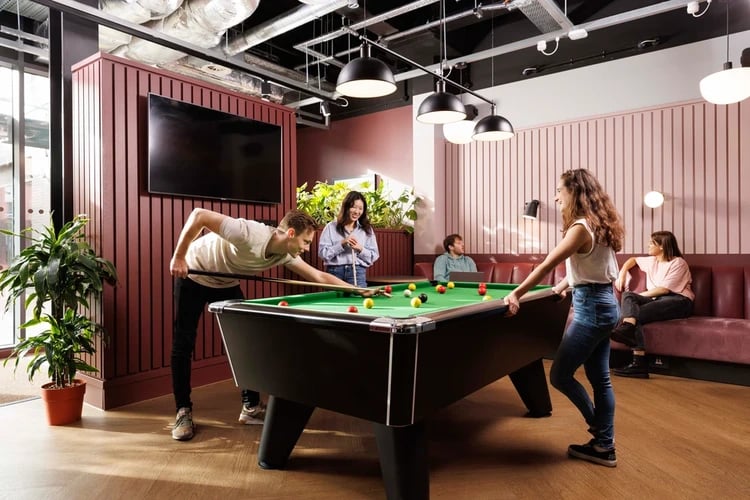 Students playing pool with TV and plants common area at Arch View House in London Student Accommodation