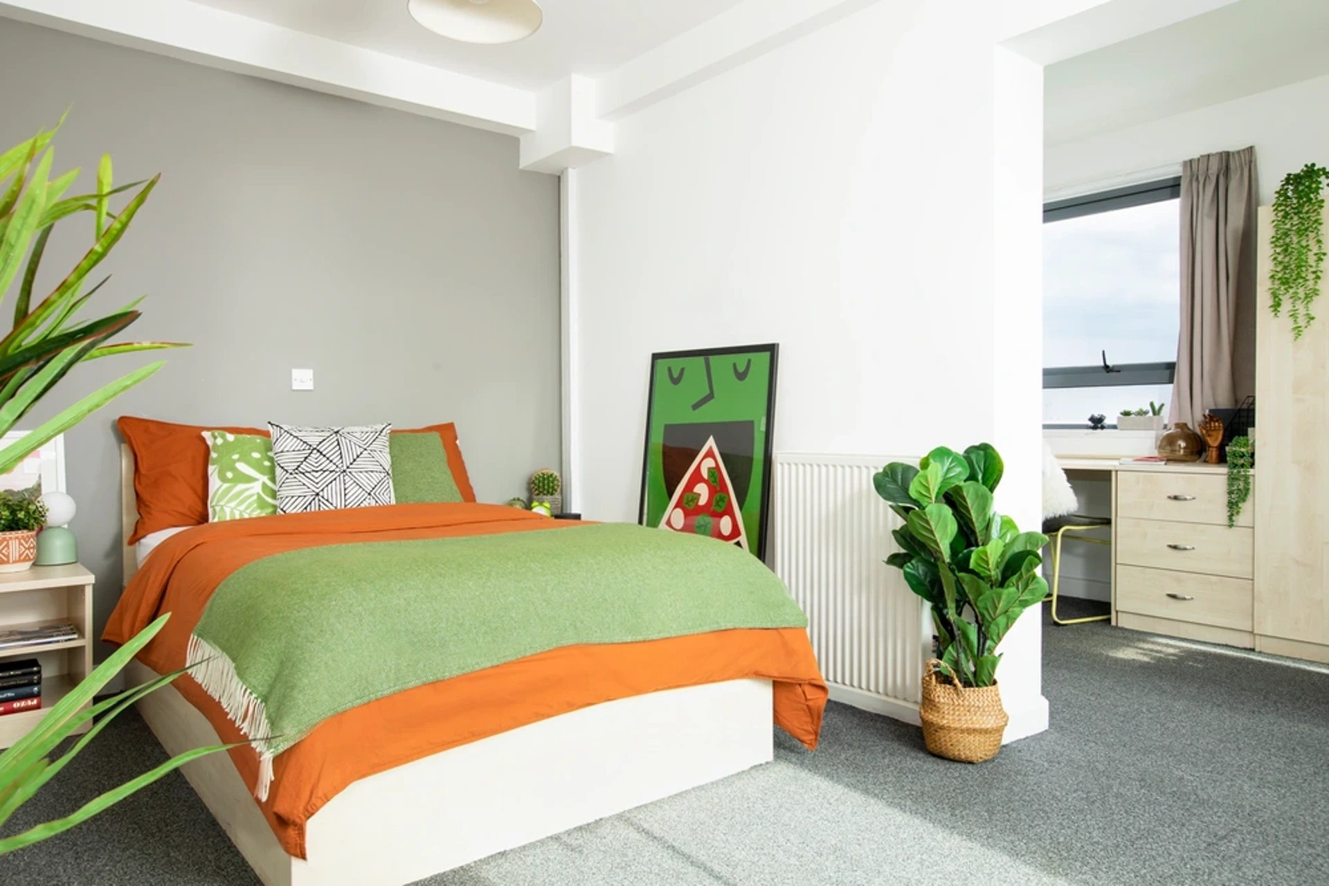 Orange bed green throw pillows framed art bedroom at Blithehale Court in London Student Accommodation
