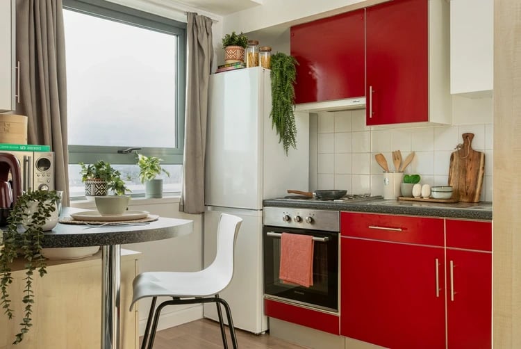 Small dining table red cabinets and white chair kitchen at Blithehale Court in London Student Accommodation