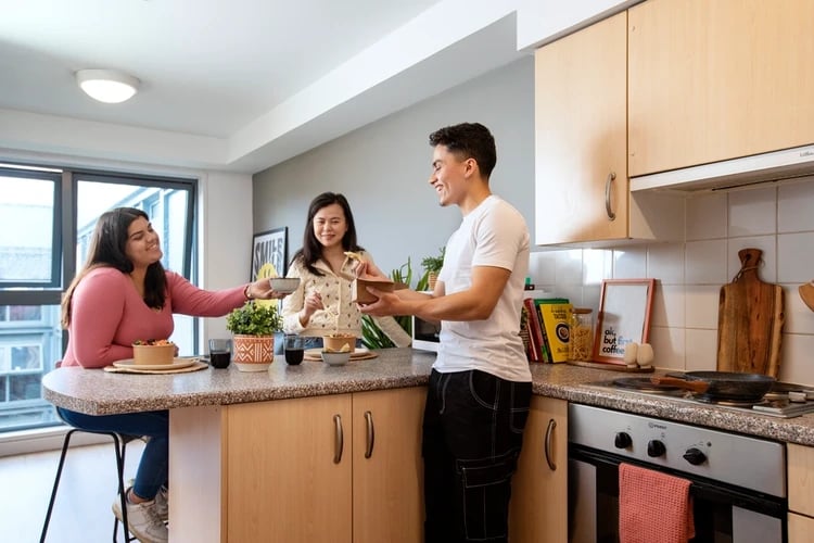 Three students preparing food at kitchen counter kitchen at Blithehale Court in London Student Accommodation