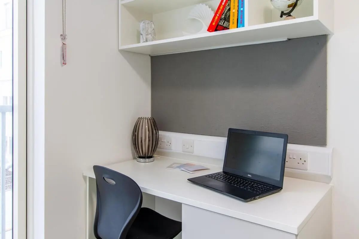 Desk chair laptop lamp shelf books study area at Plymouth Cross House in Plymouth Student Accommodation