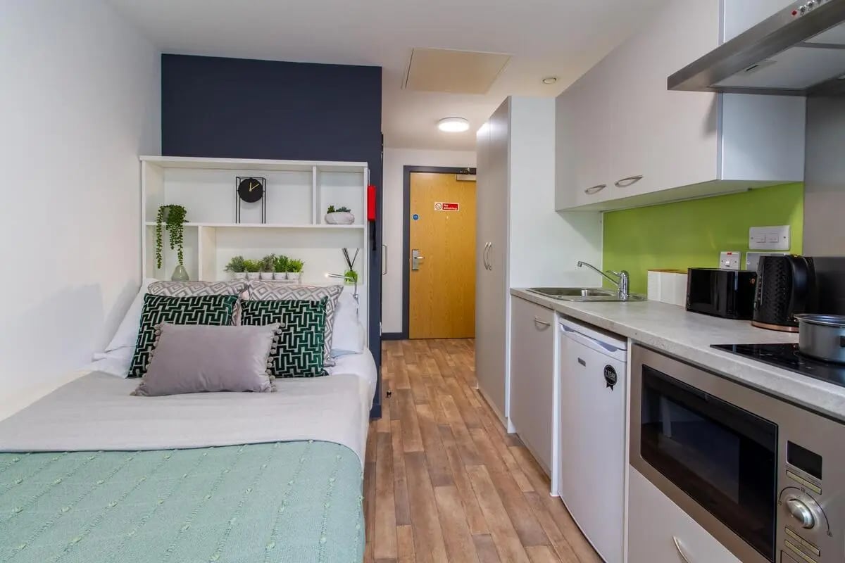 Bed with shelves kitchen with appliances studio apartment at Plymouth Cross House in Plymouth Student Accommodation