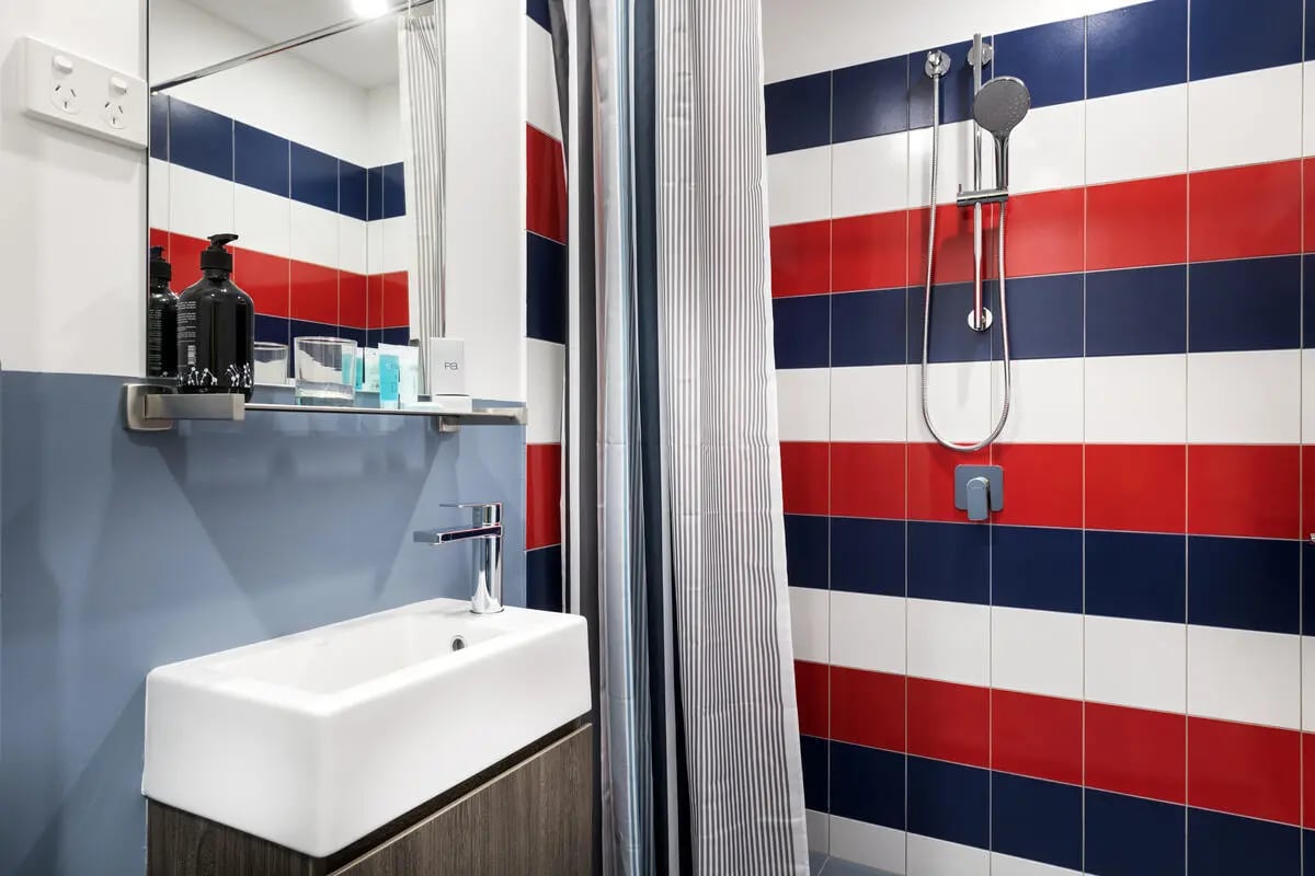 Sink showerhead toiletries striped tiled bathroom at The G Living in Perth Student Accommodation