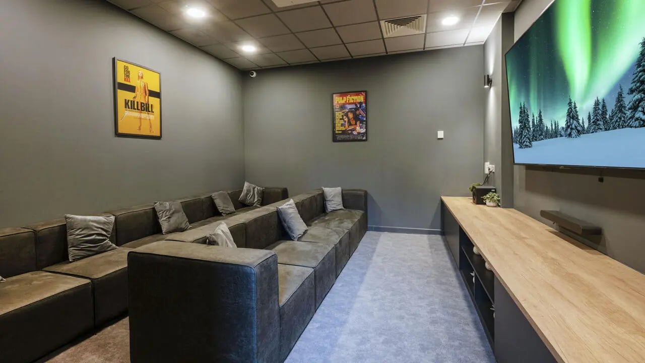 Sofa with pillows large TV wooden cabinet cinema room at St Gabriels in Manchester Student Accommodation