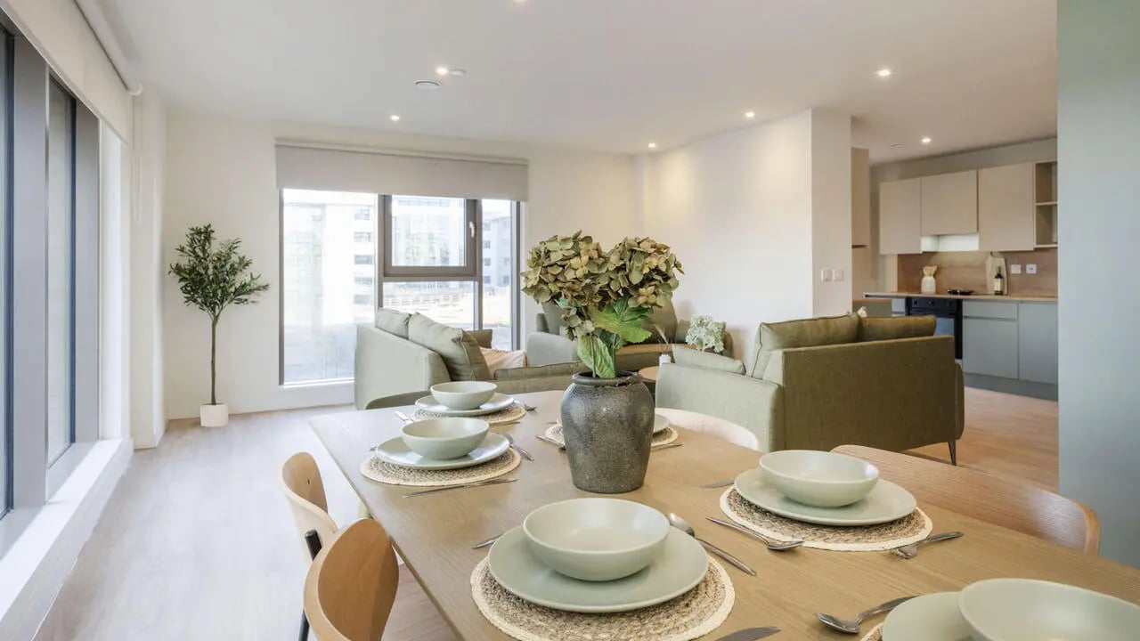 Dining table with place settings sofa and kitchen living room at City Wharf in Glasgow Student Accommodation