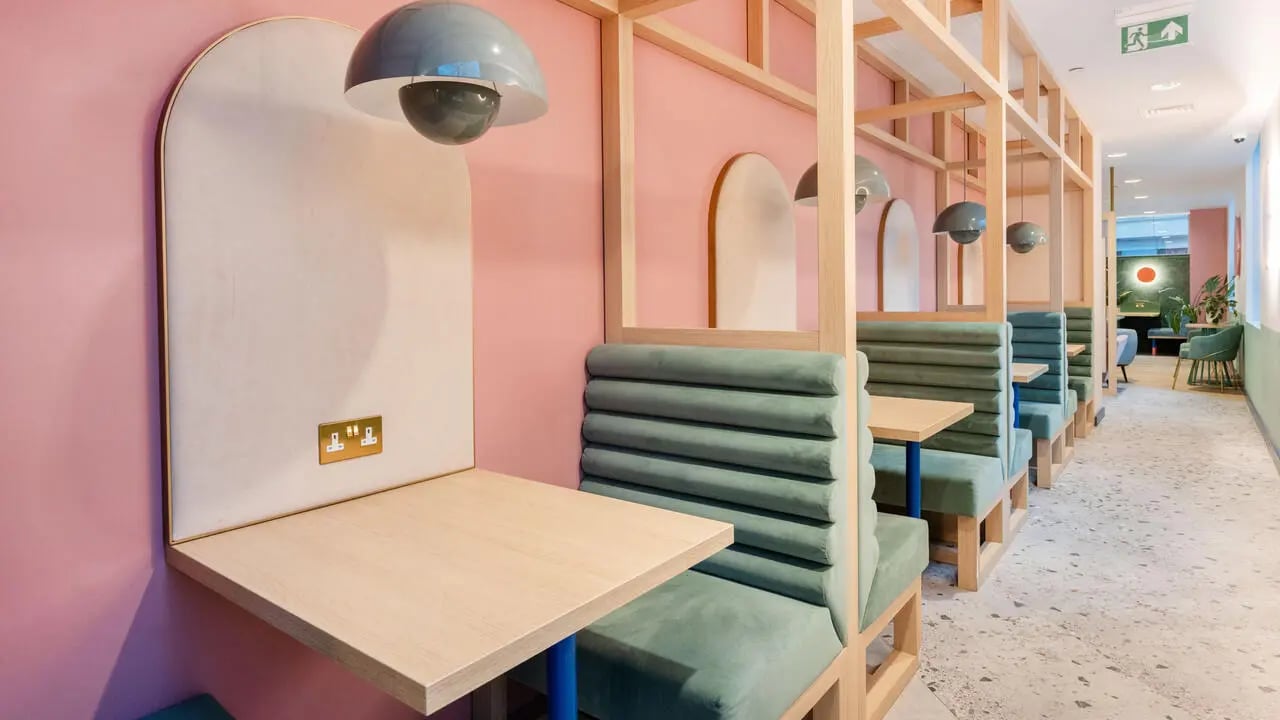 Booth seating with tables and pastel walls communal area at Wick Park in London Student Accommodation