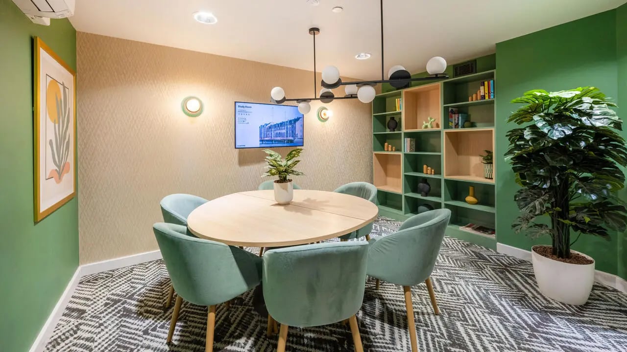 Round table with chairs green shelves study area at Wick Park in London Student Accommodation