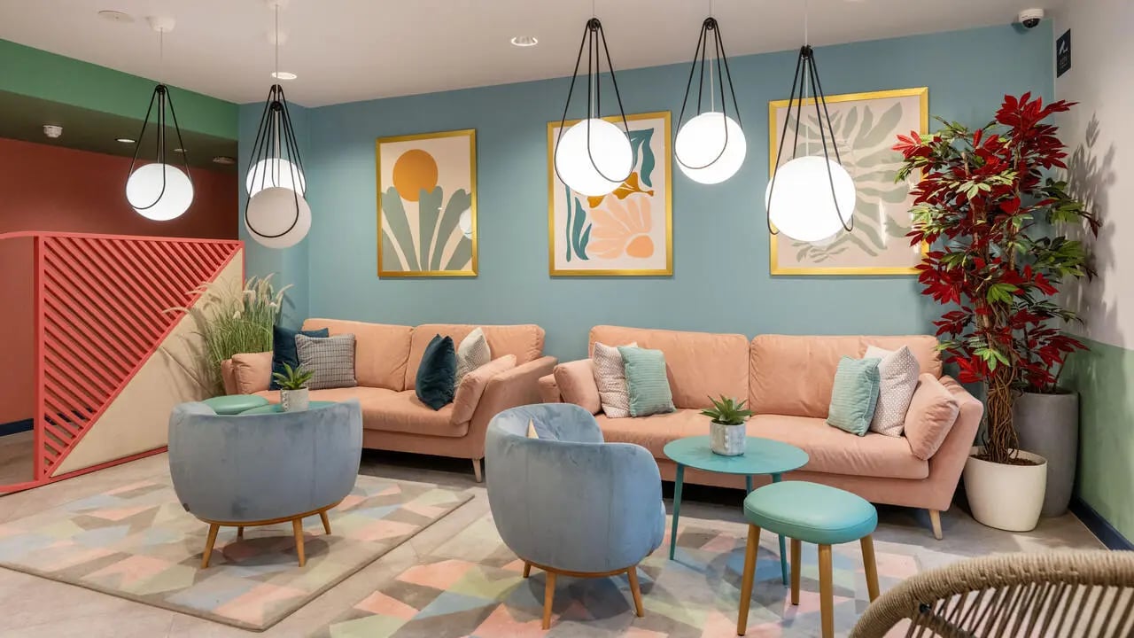 Pink sofas blue armchairs artwork living room at Wick Park in London Student Accommodation