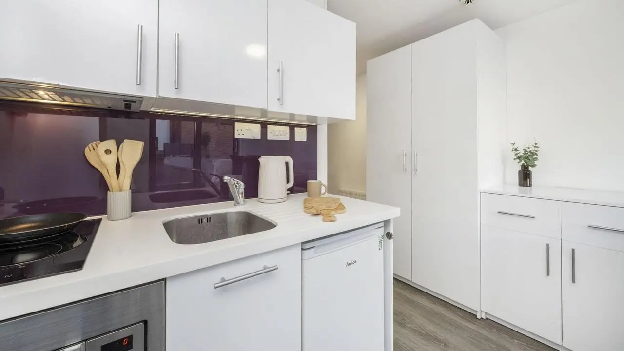 White kitchen cabinets sink kettle wooden utensils kitchen at The Cube Ealing in London Student Accommodation