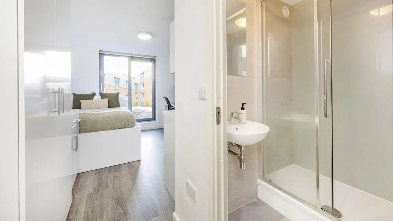 Bed desk and shower visible student room bathroom at The Cube Ealing in London Student Accommodation