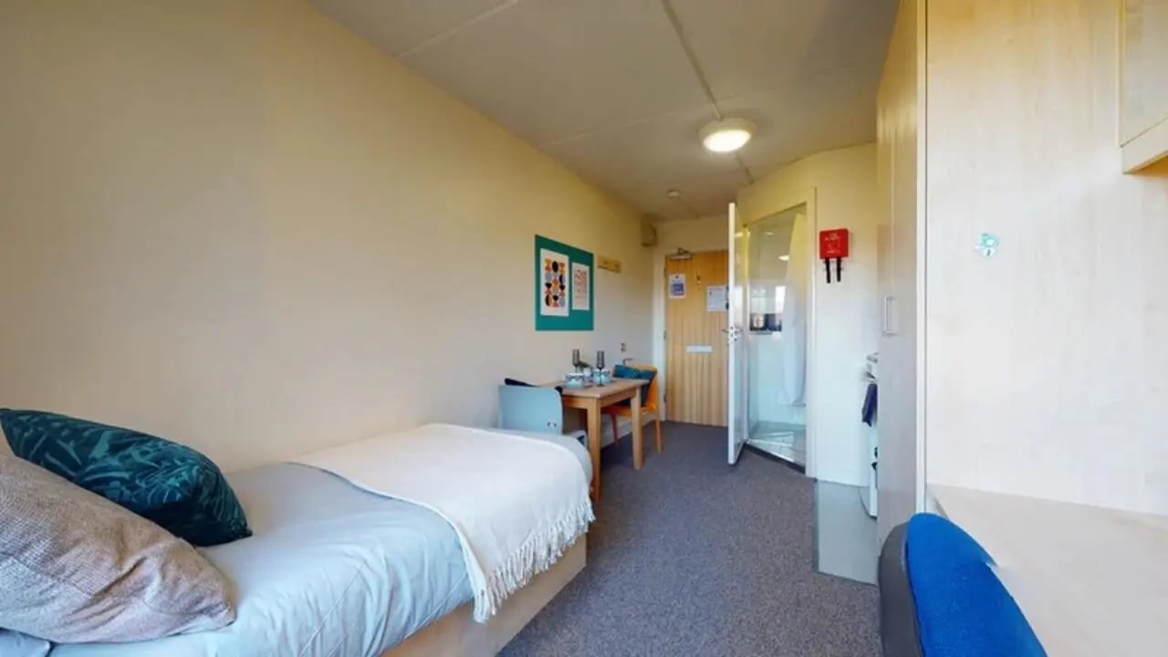 Bed table chairs shower closet bedroom at Creek Court in London Student Accommodation