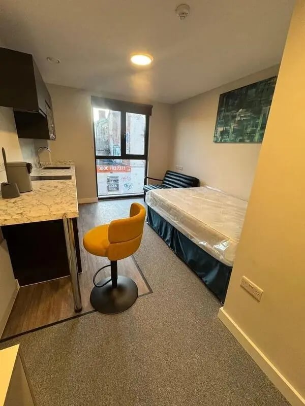 Bed kitchenette yellow stool and sofa living room at Cleveland Apartments in Wolverhampton Student Accommodation