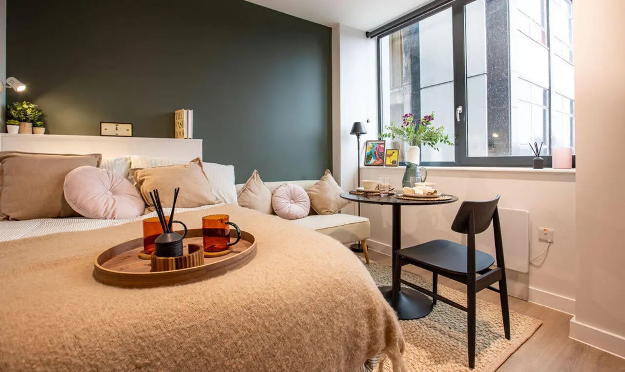 Bed with tray, sofa, table, chair studio apartment at Yugo Haüs in Birmingham Student Accommodation