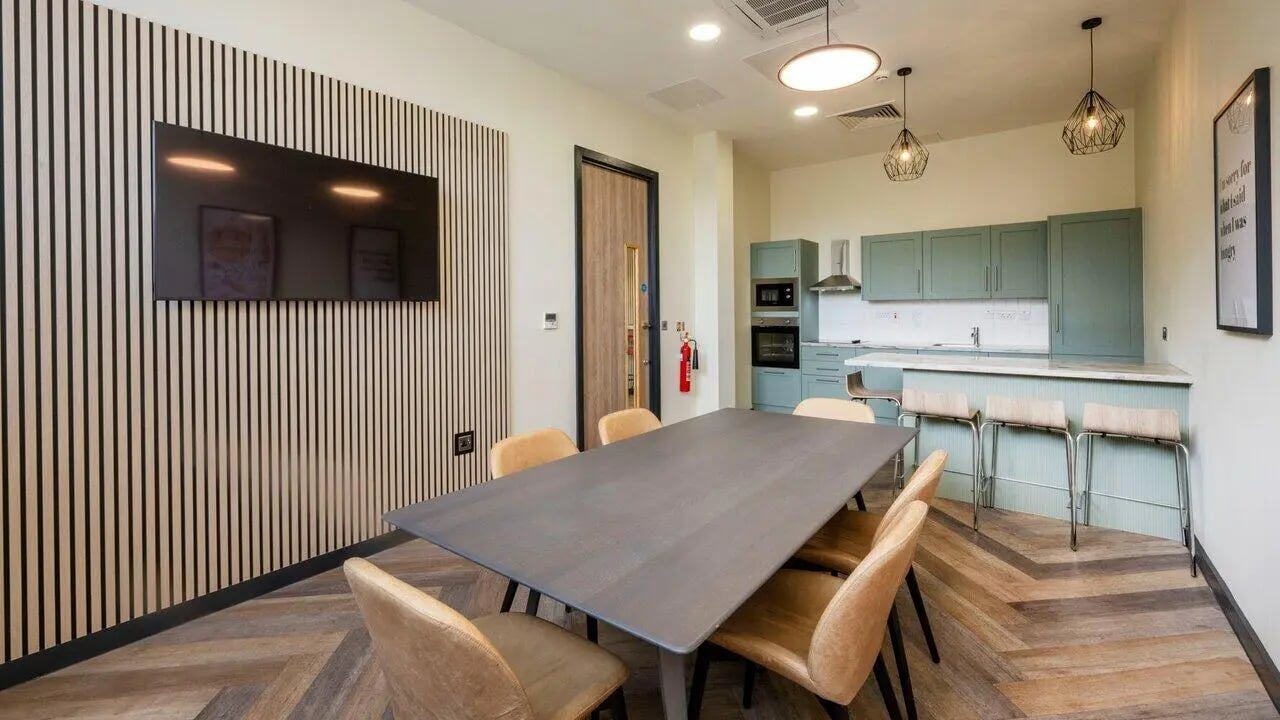 Large table with chairs and kitchen communal area at Fontenoy Apartments in Liverpool Student Accommodation