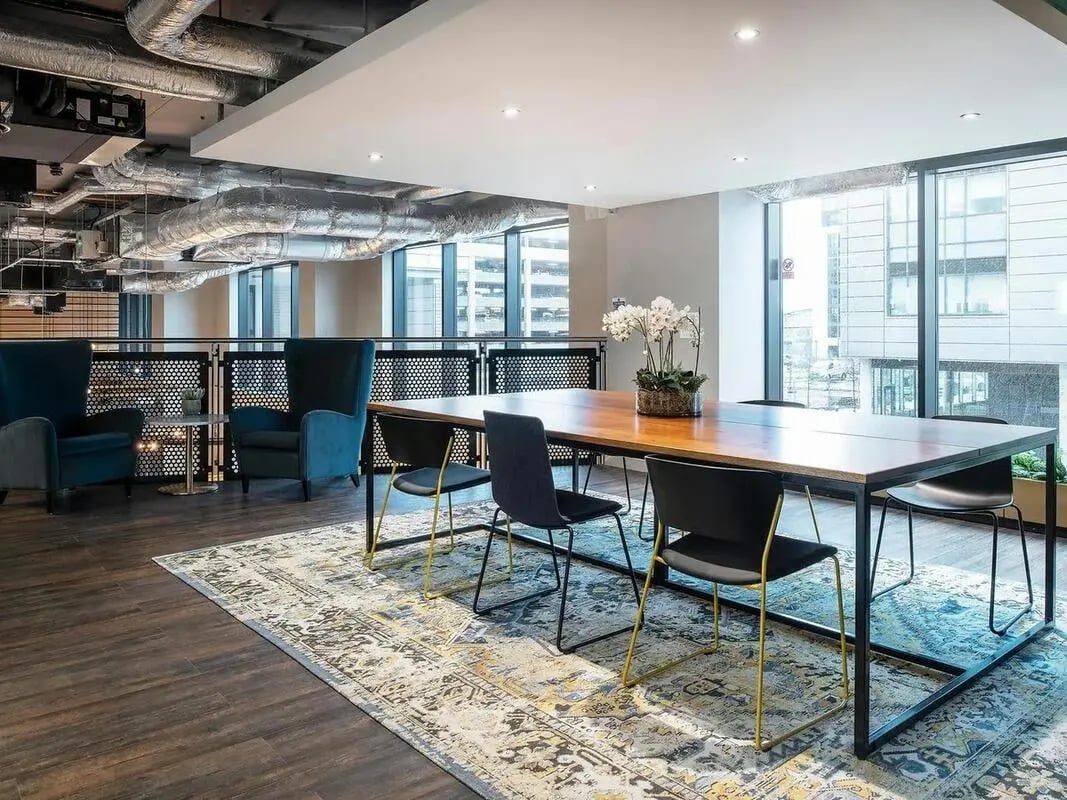 Wood table chairs rug and armchairs Common area at Zenith in Cardiff Student Accommodation