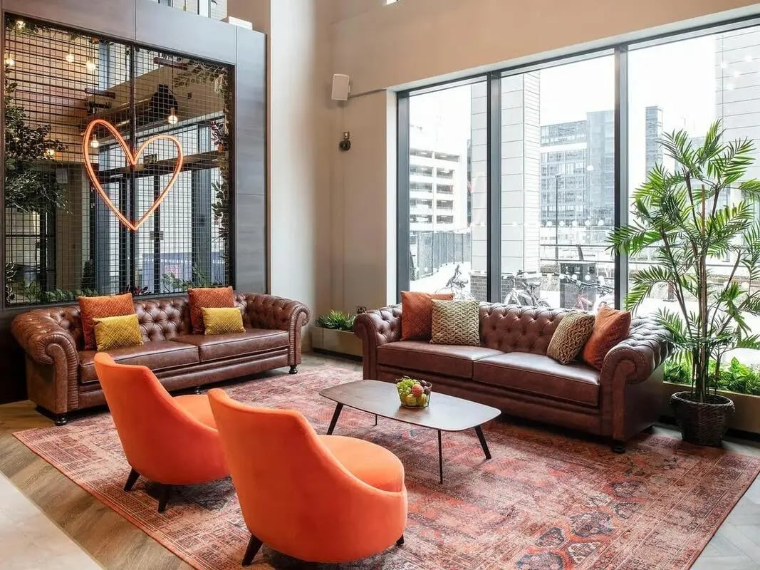 Brown leather sofas orange chairs heart neon living room at Zenith in Cardiff Student Accommodation