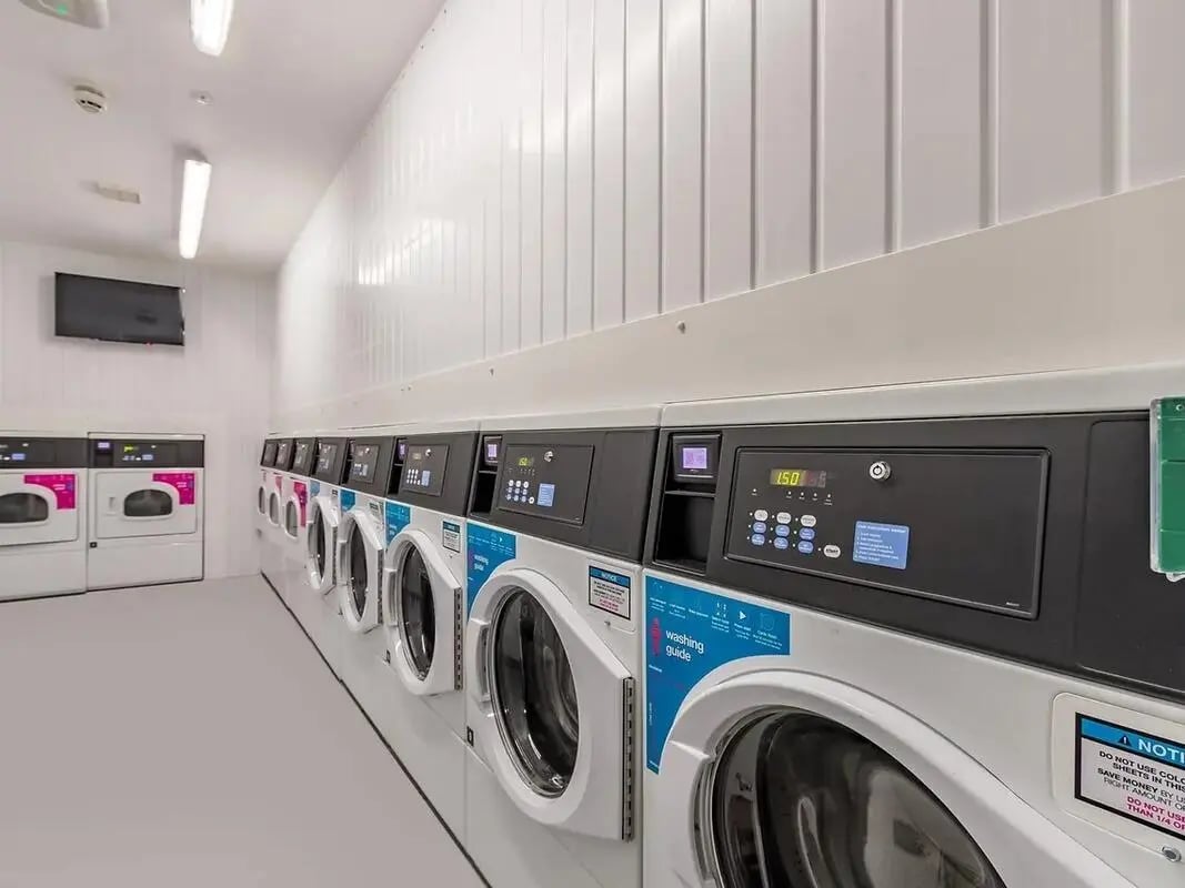 Row of washing machines with digital displays laundry room at ViBe Student Living in Kingston Upon Thames Student Accommodation