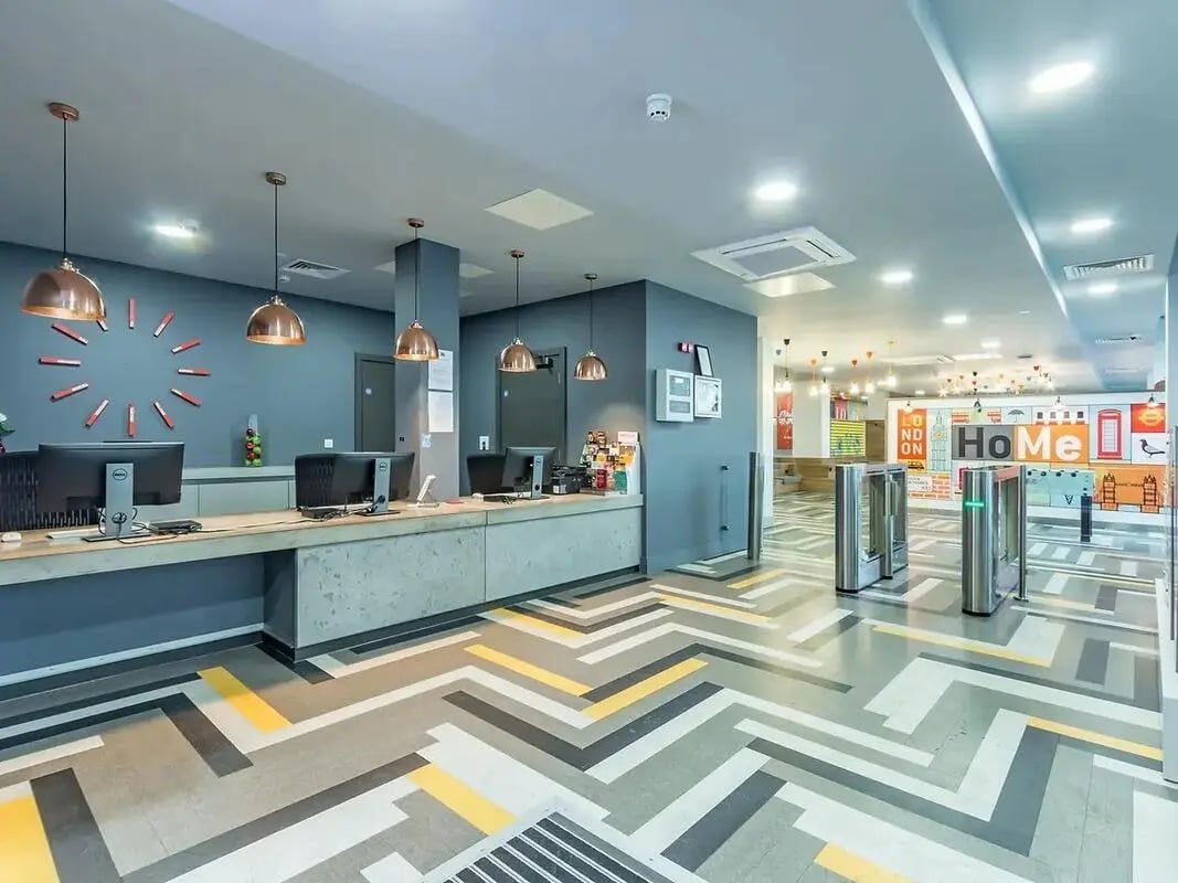 Reception desk with computers and turnstiles interior at ViBe Student Living in Kingston Upon Thames Student Accommodation