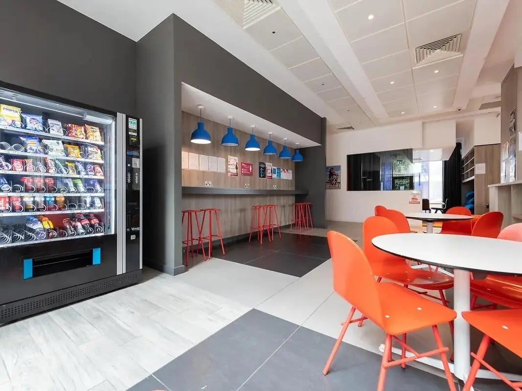 Vending machine red stools white tables orange chairs lounge at Felda House in Wembley Student Accommodation