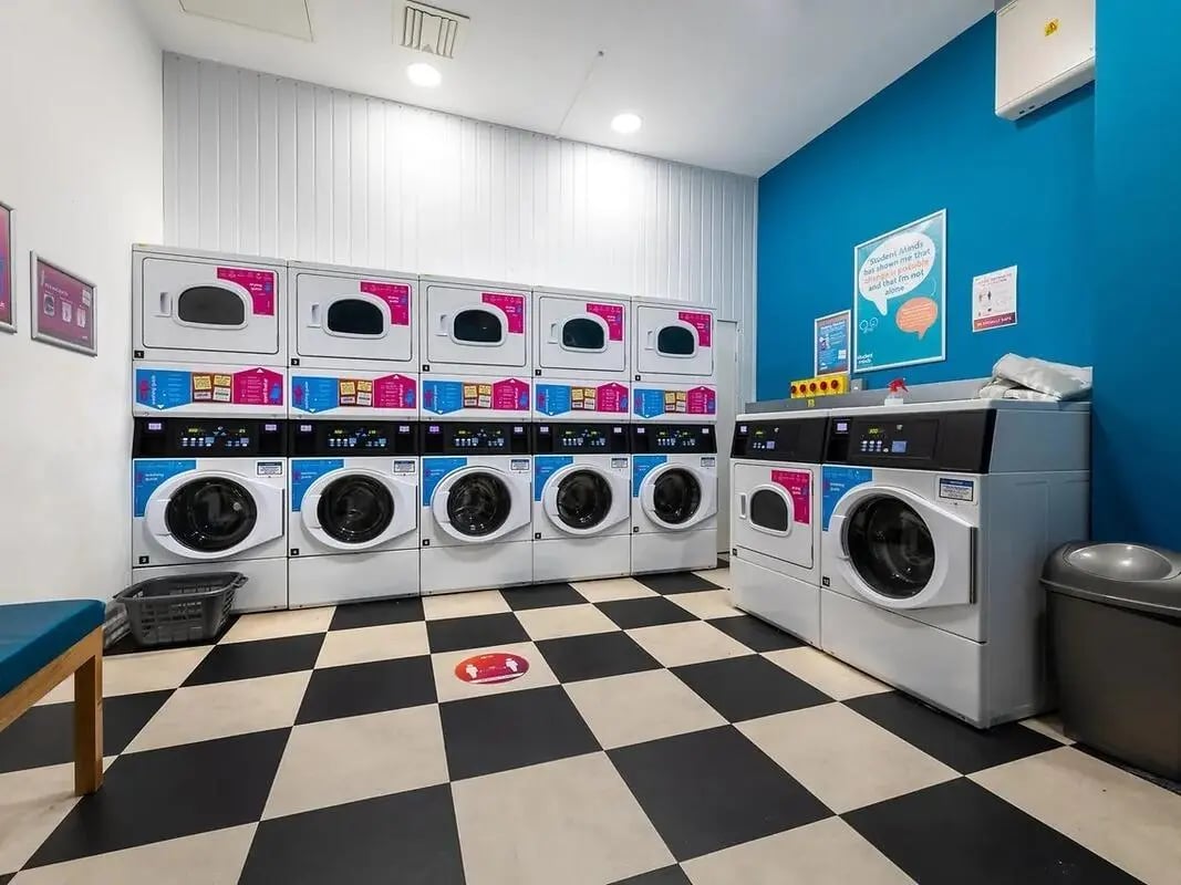 Washing machines stacked and beside dryers laundry room at Felda House in Wembley Student Accommodation
