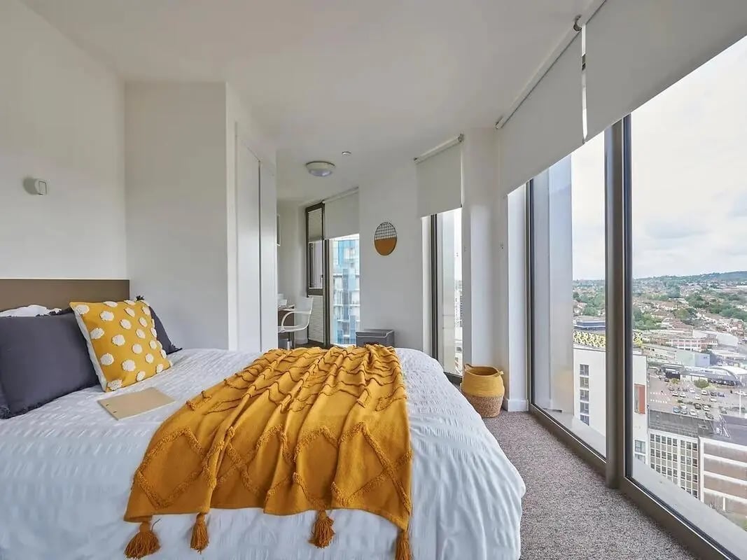 Bed with yellow throw and city view bedroom at Felda House in Wembley Student Accommodation