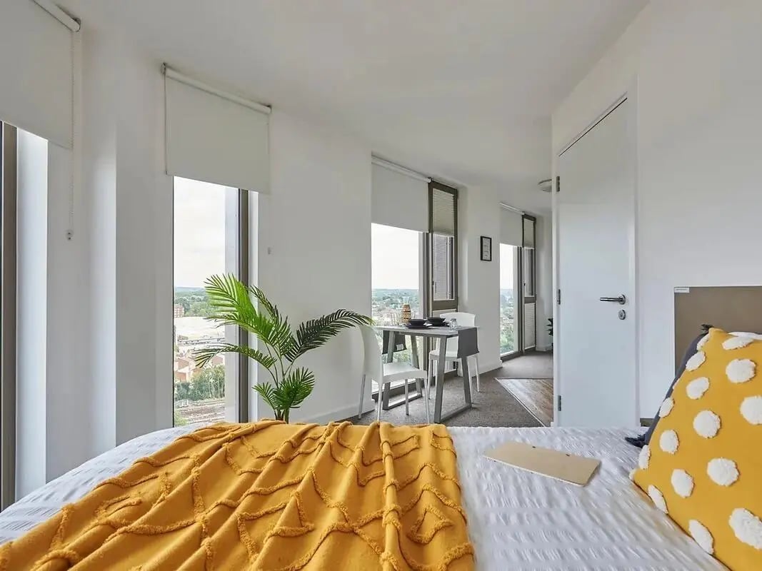 Bed with yellow blanket and table area bedroom at Felda House in Wembley Student Accommodation