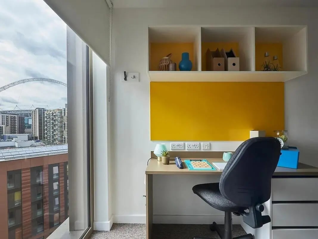 Desk chair plant blue vase shelves study area at Felda House in Wembley Student Accommodation