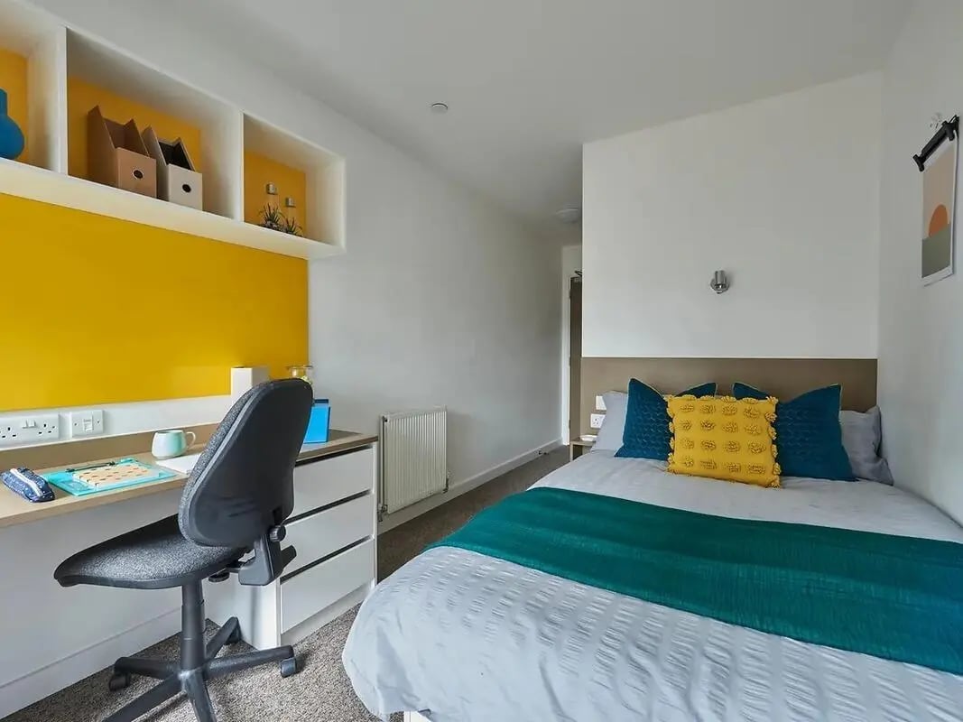Desk chair bed with yellow blue pillows bedroom at Felda House in Wembley Student Accommodation
