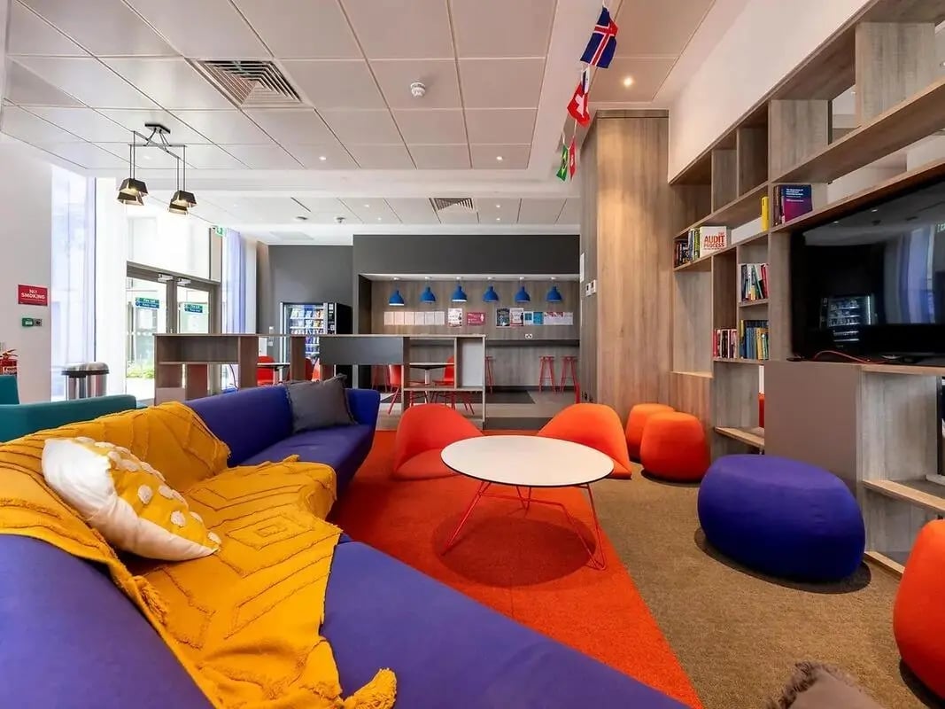 Modern communal lounge with purple sofa and orange beanbags lounge area at Felda House in Wembley Student Accommodation