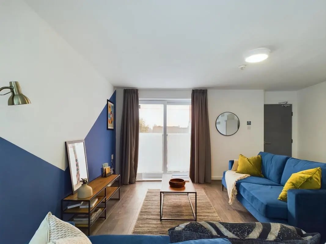 Blue sofa coffee table and patterned rug living room at 6 Bedroom House at 2, Flat 2, Windsor House, Clint Road West in Liverpool Student Accommodation