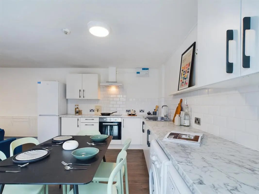 Dining table with plates bowls kitchen counter exterior at 6 Bedroom House at 2, Flat 2, Windsor House, Clint Road West in Liverpool Student Accommodation