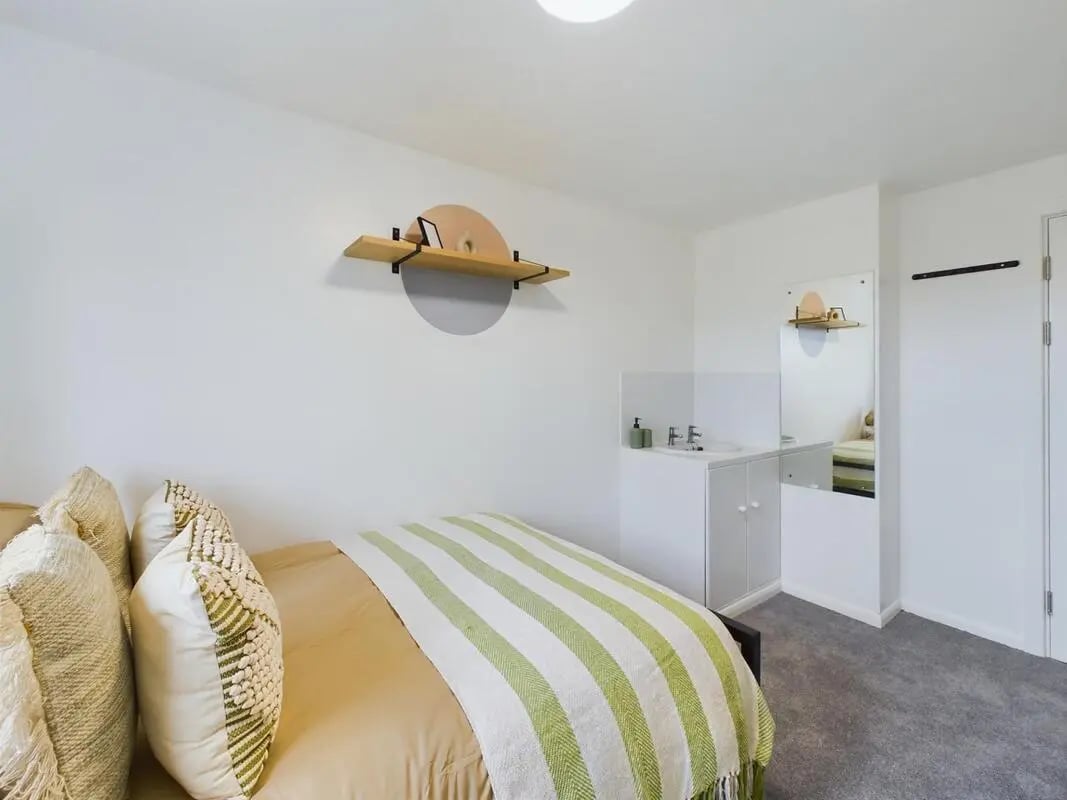 Bed with green striped blanket sink area Bedroom at 6 Bedroom House at 1, Sage Road in Leicester Student Accommodation