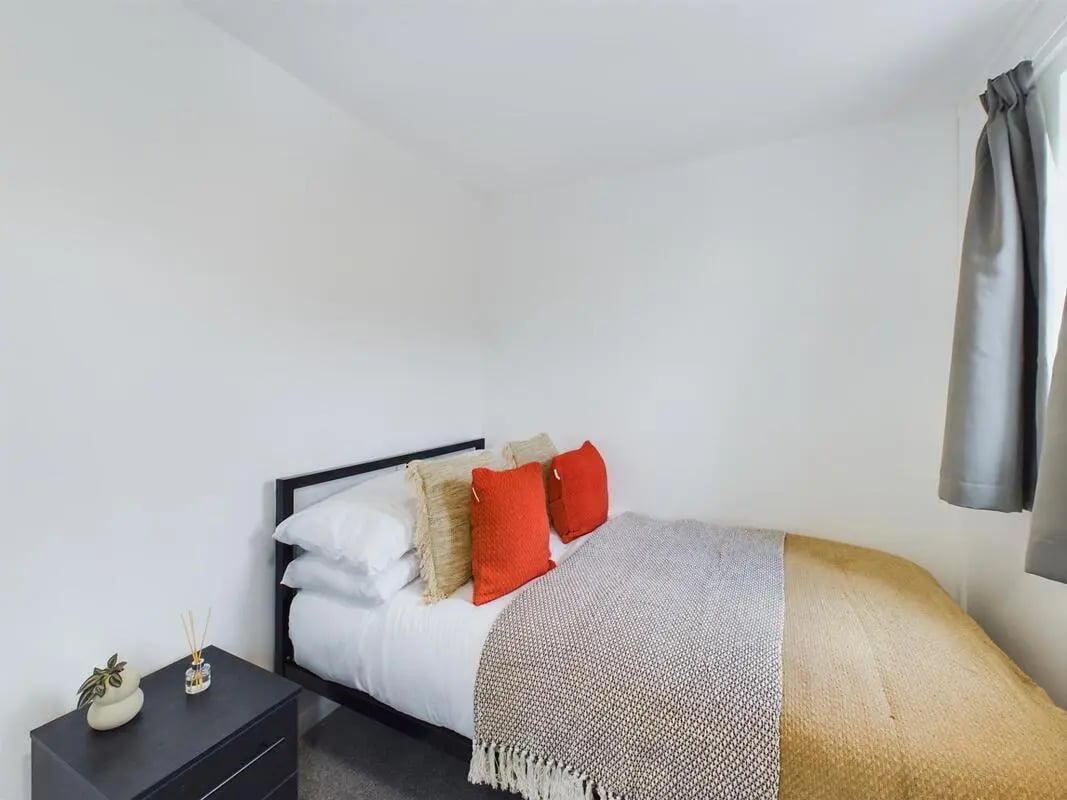 Bed with pillows and blanket bedside table bedroom at 6 Bedroom House at 9, Sage Road in Leicester Student Accommodation