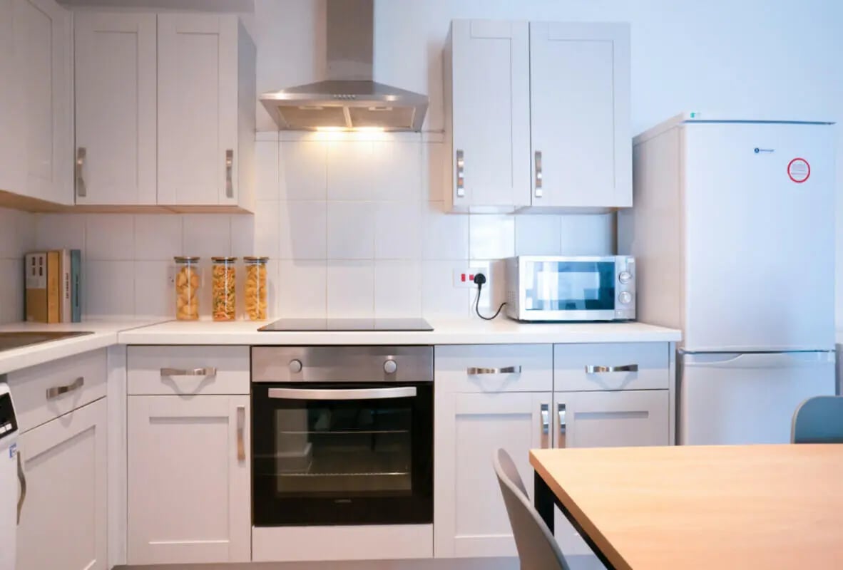 White cabinets stove oven microwave refrigerator kitchen at 8 Bedroom House at 79, Crofton Street in Manchester Student Accommodation