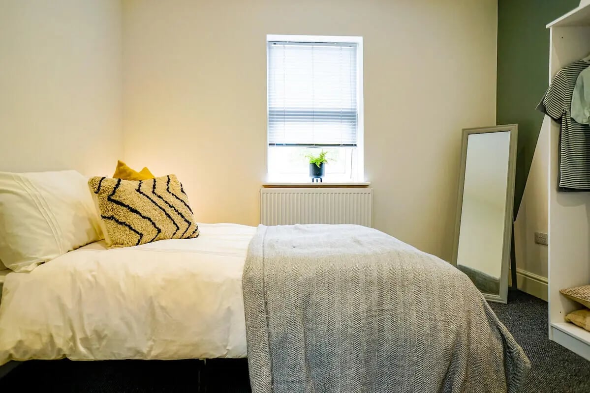 Bed with patterned pillows mirror and wardrobe bedroom at 6 Bedroom House at 3, Baggholme Road in Lincoln Student Accommodation