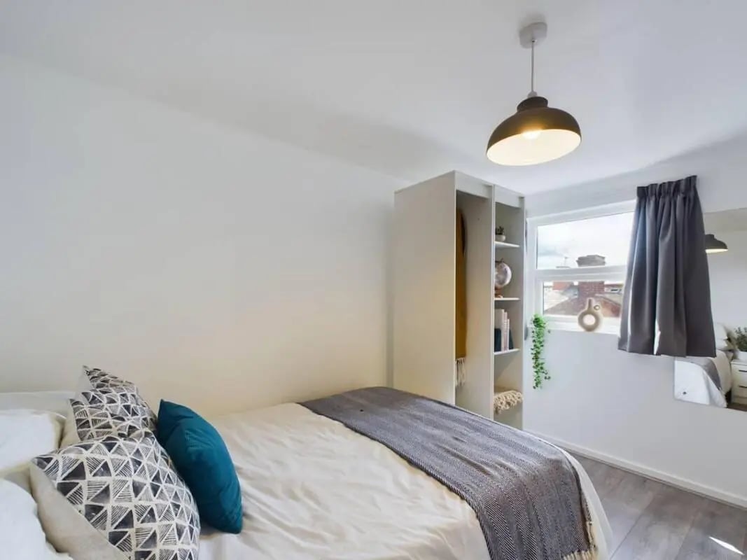 Bed with patterned pillows grey throw wardrobe and window bedroom at 5 Bedroom House at 2, Crofton Street in Manchester Student Accommodation