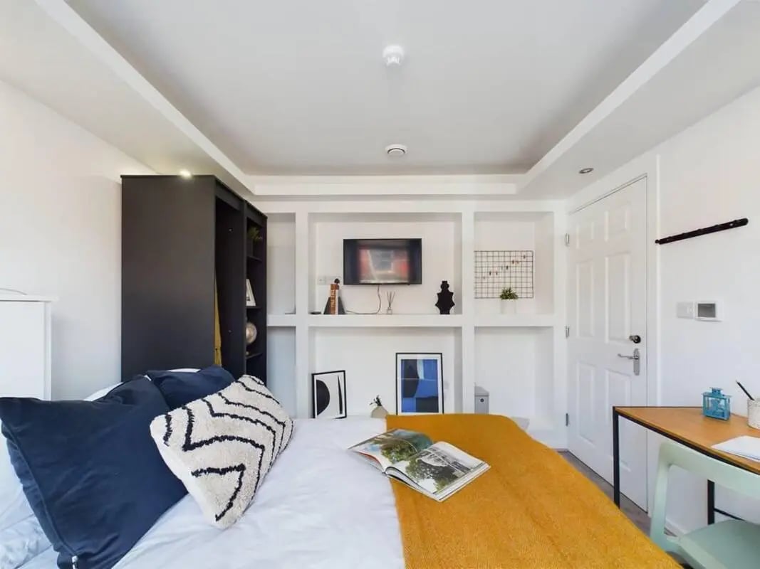 Bed with pillows yellow blanket bookshelf TV bedroom at 5 Bedroom House at 2, Crofton Street in Manchester Student Accommodation